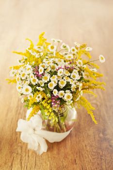 Beautiful bouquet of wildflowers in vase on wooden background