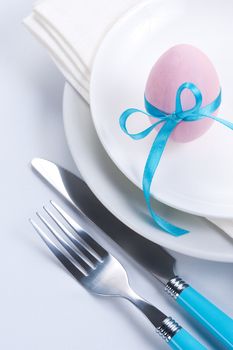 Easter table setting with plates, napkin, silverware and easter egg