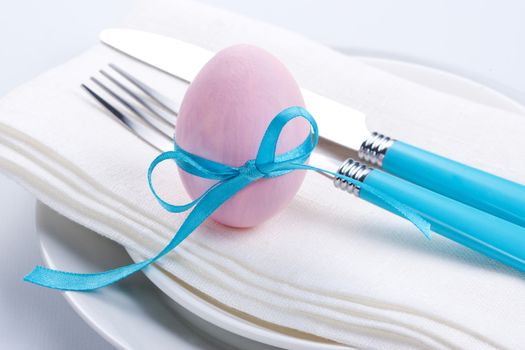 Easter table setting with plates, napkin, silverware and easter egg