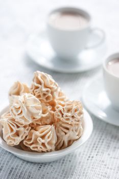 Meringues and two cups of chocolate drink, shallow dof.