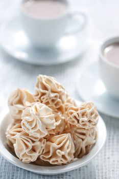 Meringues and two cups of chocolate drink, shallow dof.