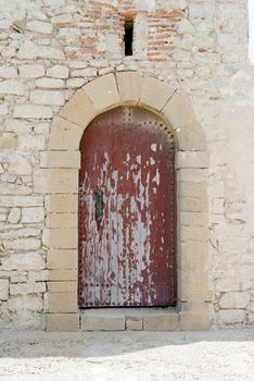 An old red door in arch looking weather in Marrakech, Morocco