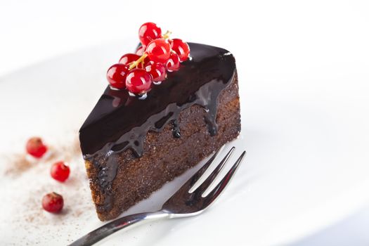 Piece of chocolate cake with red berries on white background
