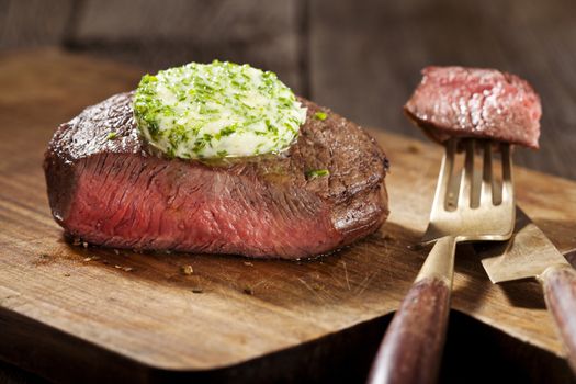 Steak with green butter on wooden board