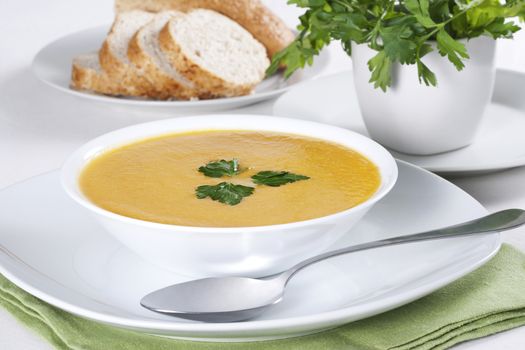 A bowl of soup with parsley and few slices of bread