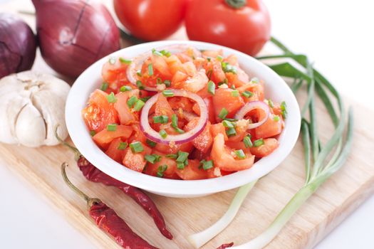 Salsa in a bowl on a wooden board and the ingredients: tomatoes, onions, garlic, chili pepper