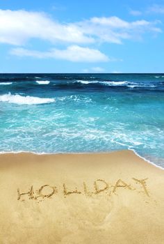 Word Holiday written in summer vacation sea beach sand