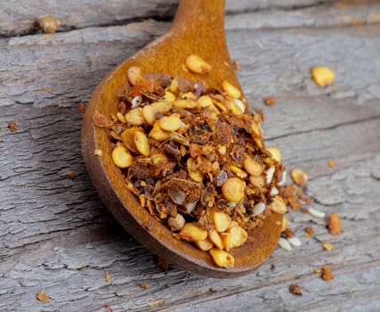 Wooden Spoon with Dried Chili Flakes closeup on Wooden background