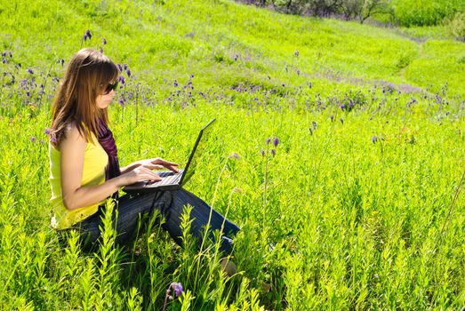 Young beautiful woman with laptop outdoor. Sunny summer day.