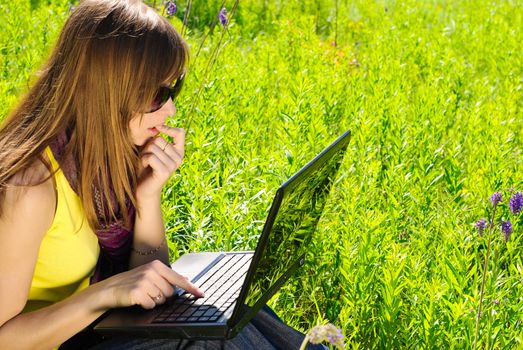 Young beautiful woman with laptop outdoor. Sunny summer day.