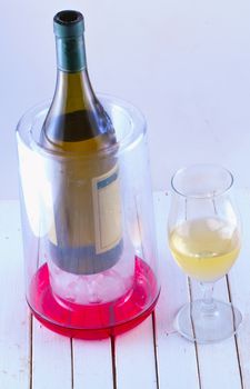 Bottle of wine in a thermo, with glass, over wooden table