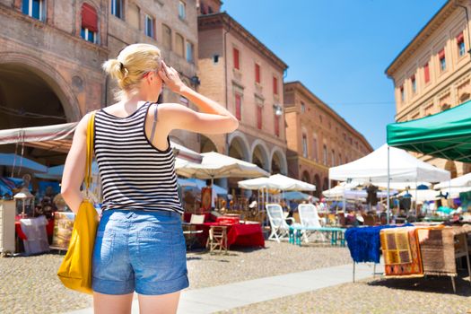 Lady walking the flea market on old traditional Piazza of Santo Stefano square of Bologna, Italy.