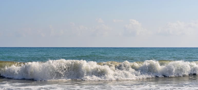 Sea wave rolled ashore. Blue sky in the background