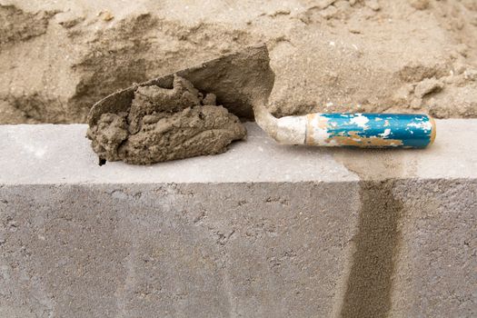 Trowel with concrete on a constructed wall outdoors