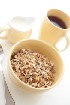 High key image of a healthy wholesome breakfast with a bowl of muesli with a jug of milk and mug of freshly brewed filter coffee