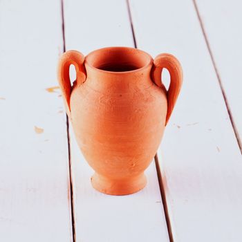 Amphora in terracotta over white wooden table