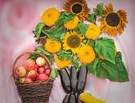Decorative bouquet from flowers of a sunflower, vegetables and the basket filled with ripe apples.