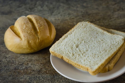 fresh bun and slice  bread on dish over  wooden  background