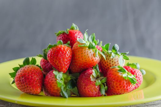 still life of fresh red strawberries on dish over wooden background