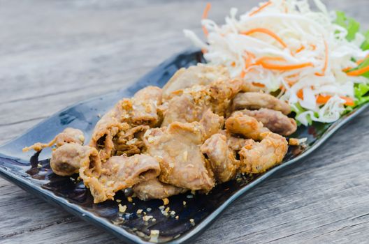 pork chitterlings fried served with fresh vegetable on dish