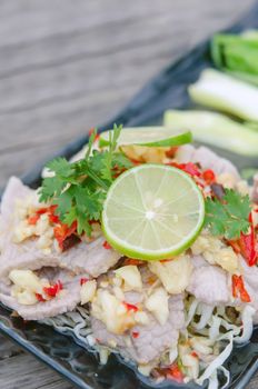 close up spicy pork served with chili sauce , fresh lime on top and fresh kale