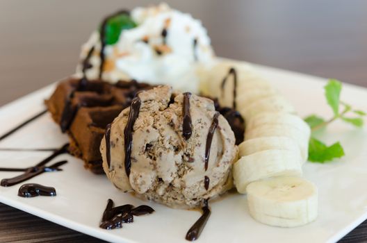 ice cream , banana , chocolate waffles with chocolate sauce and whipping cream