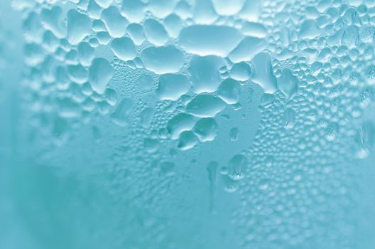 Water droplets on the glass with a colored background. Drops of water.