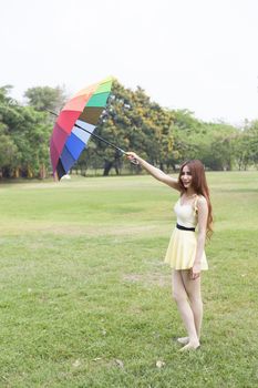 Woman with umbrella standing on the lawn. In the park during the day, the sun is strongest.