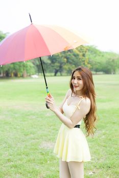 Woman with umbrella standing on the lawn. In the park during the day, the sun is strongest.