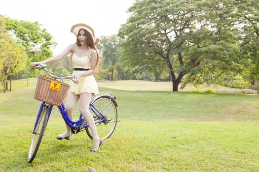 Asian woman riding a bicycle On the grass in the park. Woman wear long hair