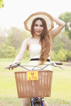 Woman riding a bicycle. Woman with hat riding a bicycle in the park.