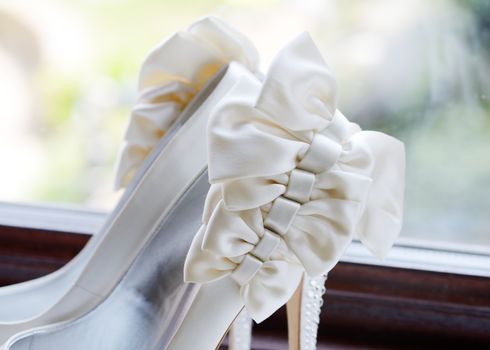 Brides shoes closeup on wedding day showing detail of bow decoration in white