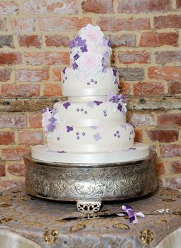Wedding cake and knife on table at reception showing details of purple floral decoration