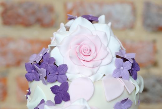 Pink and purple floral detail on top of wedding cake
