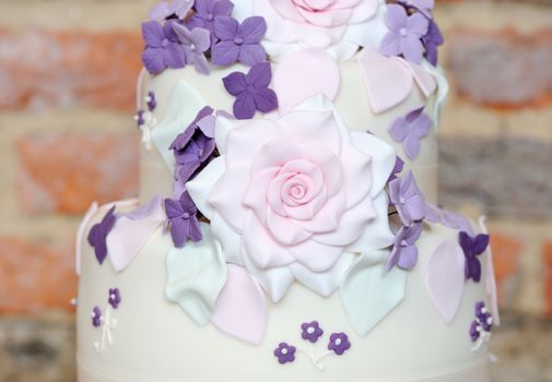 Closeup of wedding cake showing pink and purple flower decoration at reception
