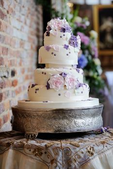 Wedding cake at reception with pink and purple flower decoration