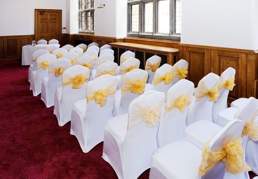 Wedding ceremony furniture and chairs with white covers and yellow ribbon