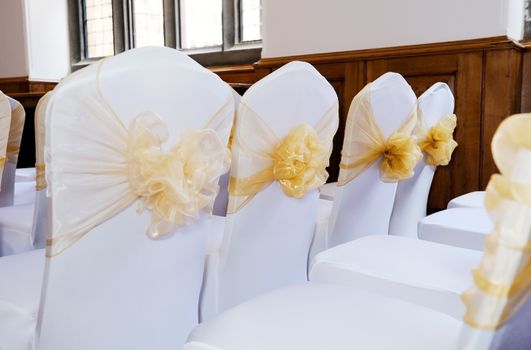Wedding ceremony chairs with white covers and yellow bows
