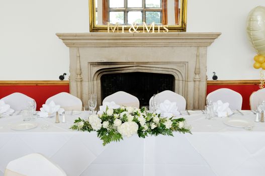Top table at wedding reception decorated with white floral arrangement