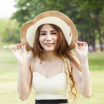 Woman holding a hat. Happy and relaxed in the relaxation area of the park.