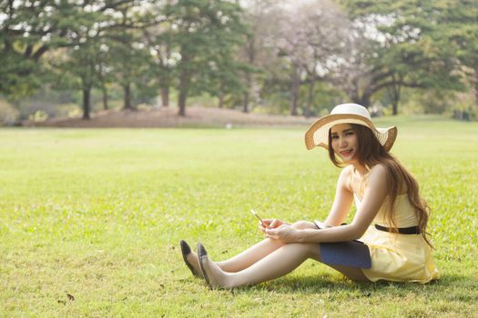 Woman using a phone Sitting on the grass in the park.