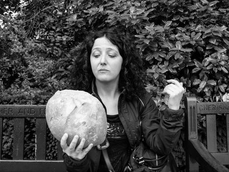 To eat or not to eat - Portrait of pretty young brunette looking at huge bread in hamletic pose