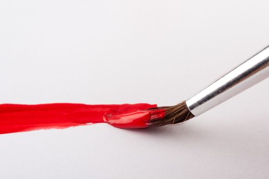 paint brush with red paint on white paper