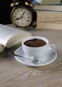 freshly brewed cup of fragrant coffee on a table among books