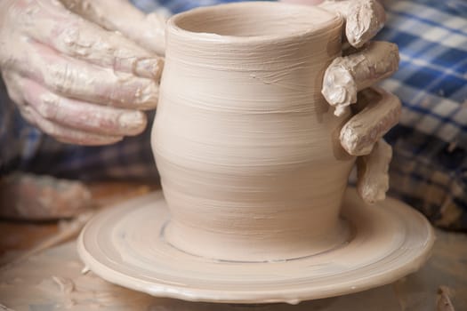 Hands of a potter, creating an earthen jar on the circle