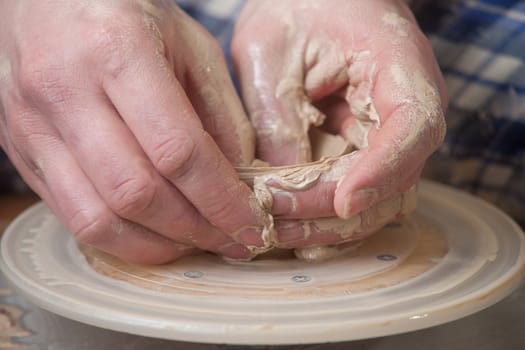 Hands of a potter, creating an earthen jar on the circle