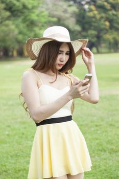 Woman play smart phones. Woman with hat standing in a park with a phone.