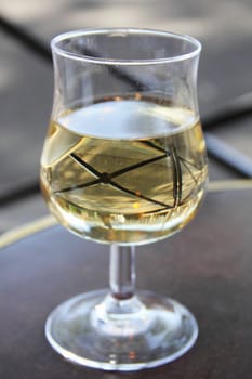 Wineglass with white wine on table in street cafe