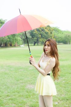 Woman with umbrella standing on the lawn. In the park during the day, the sun is strongest.