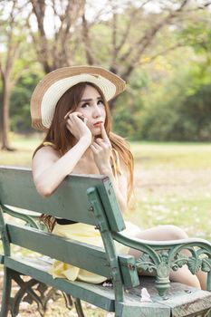 Woman talking on the phone Sitting on a bench in the park.